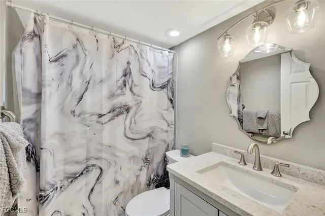a bathroom with a granite countertop toilet sink and mirror