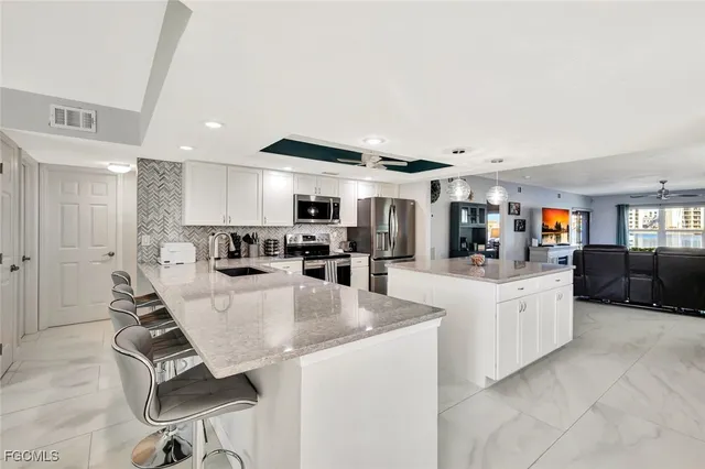a large white kitchen with a large window and stainless steel appliances