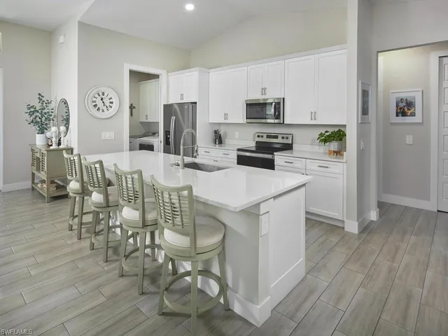 a kitchen with stainless steel appliances granite countertop a stove a refrigerator a sink a dining table and chairs with wooden floor