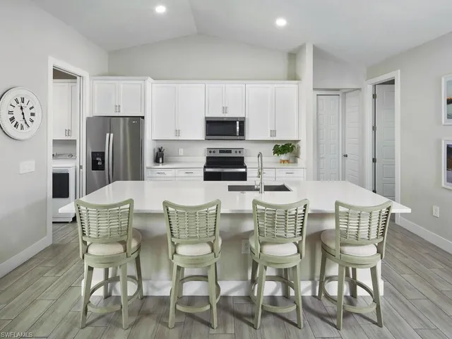 a kitchen with stainless steel appliances a dining table chairs and a refrigerator