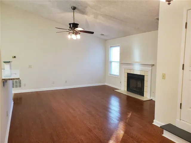 a view of empty room with wooden floor and fireplace