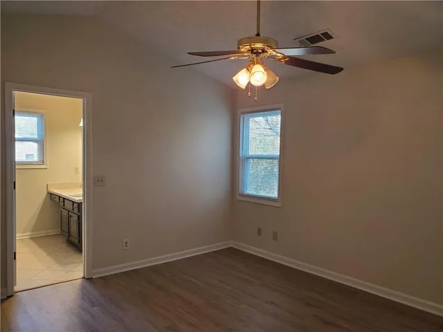 an empty room with wooden floor cabinet and windows