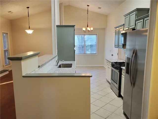 a kitchen with stainless steel appliances granite countertop a refrigerator a sink and a stove