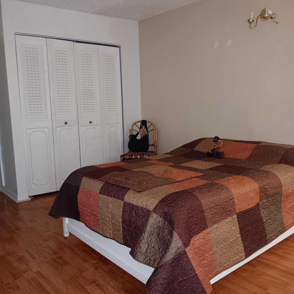 3450 Blue Lake Drive, Unit 204 Pompano Beach, FL 33064 - Photo 13 of 18 a bedroom with a bed and wooden floor