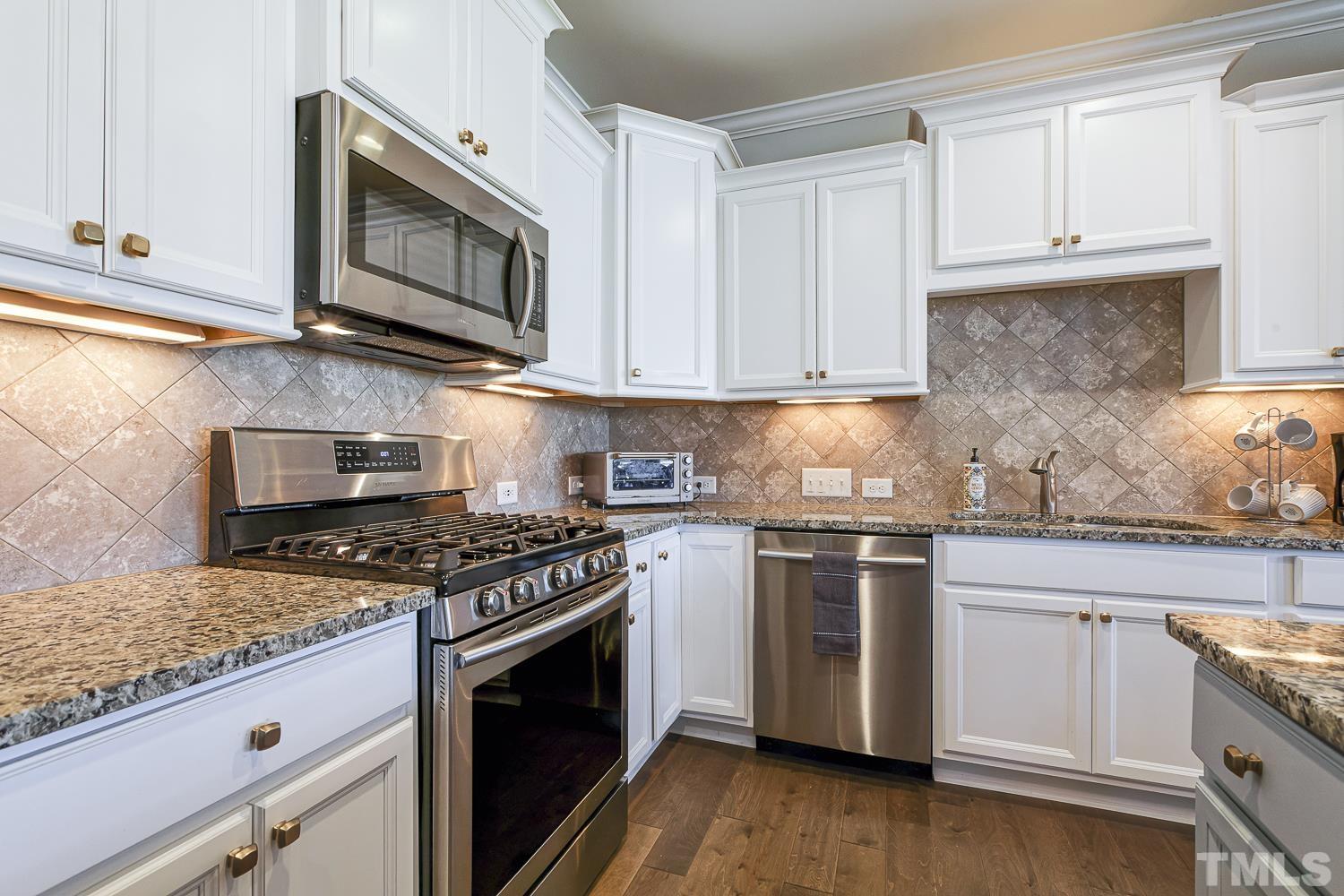5516 Red Line Court Raleigh, NC 27603 - Photo 7 of 39 a kitchen with granite countertop a stove top oven microwave and cabinets