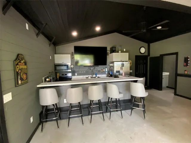 a large kitchen with stainless steel appliances a sink table and chairs in it