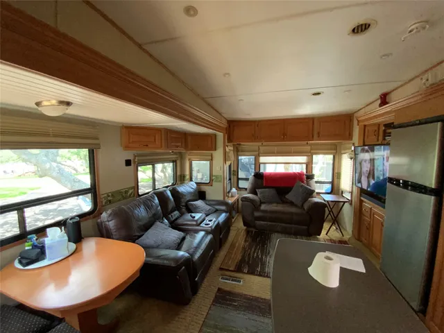 a living room with furniture a large window and stainless steel appliances