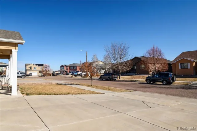 a view of a white house with a big yard and large trees