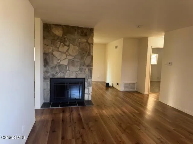 an empty room with wooden floor a fireplace and windows