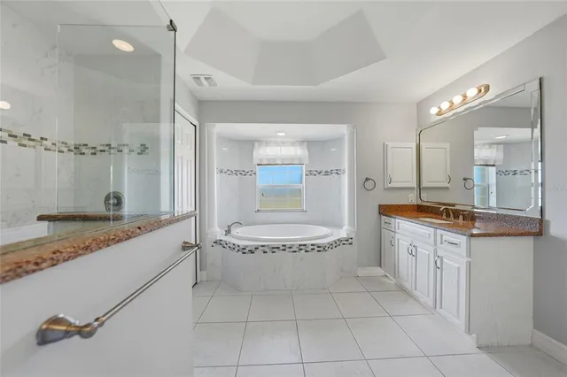 a bathroom with a granite countertop sink a mirror and a bathtub