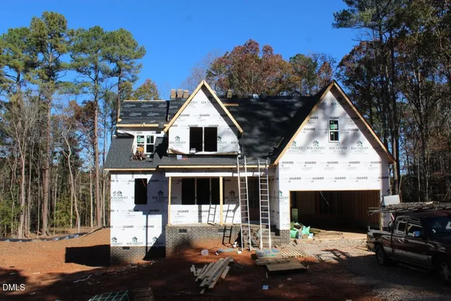 a view of house with yard outdoor seating and covered with trees