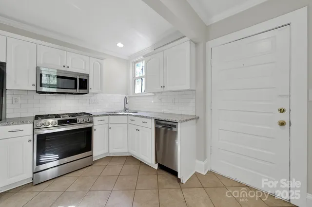 a kitchen with granite countertop a refrigerator a stove top oven and a sink