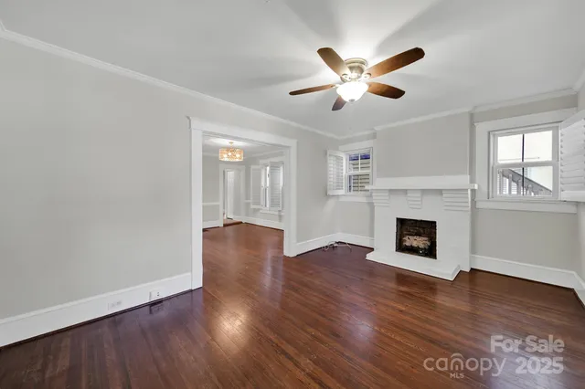 a view of an empty room with wooden floor fireplace and a window