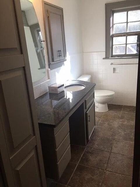 2915 21st Street Lubbock, TX 79410 - Photo 13 of 18 a bathroom with a granite countertop sink a toilet a mirror and a window