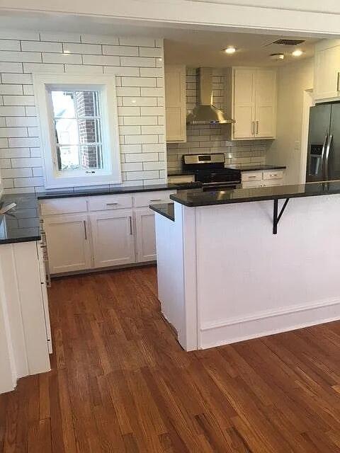 2915 21st Street Lubbock, TX 79410 - Photo 4 of 18 a kitchen with kitchen island granite countertop a stove a sink and white cabinets with wooden floor