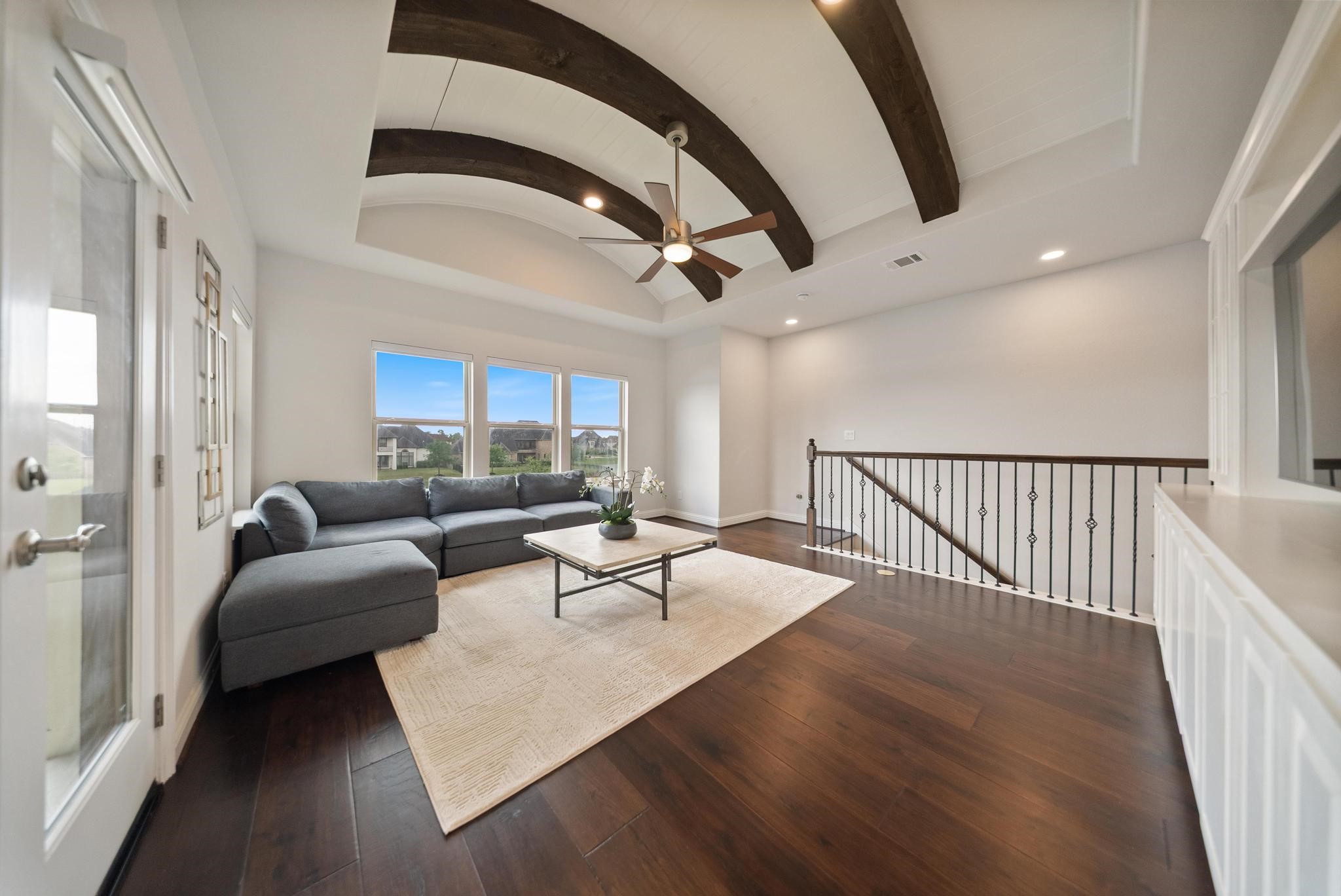 5403 Rouchel Brook Lane Sugar Land, TX 77479 - Photo 24 of 42 Spacious upstairs game room/living area with vaulted ceilings, exposed beams, and an access to second staircase. Featuring custom built-ins perfect for organization and keeping the room clean. With access to the balcony and extended patio overlooking the backyard and serene lake.