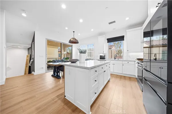a large kitchen with stainless steel appliances a sink a window and a living room view
