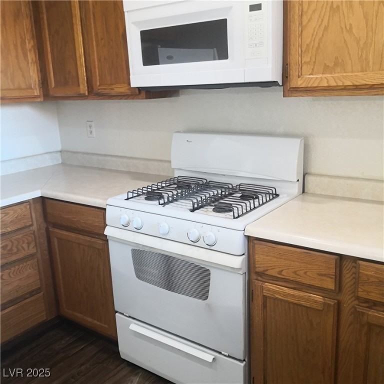 5026 South Rainbow Boulevard, Unit 203 Las Vegas, NV 89118 - Photo 12 of 31 Kitchen featuring white appliances, brown cabinetry, light countertops, and dark wood-type flooring