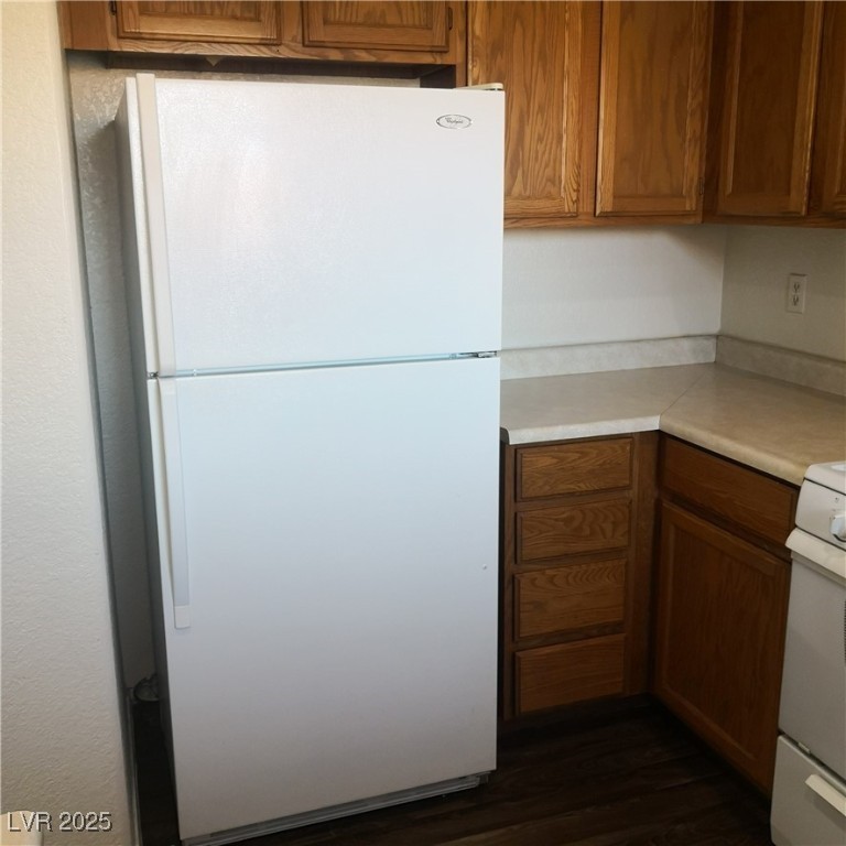 5026 South Rainbow Boulevard, Unit 203 Las Vegas, NV 89118 - Photo 13 of 31 Kitchen with brown cabinetry, light countertops, white appliances, and dark wood-type flooring