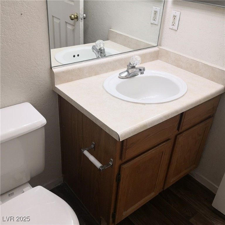 5026 South Rainbow Boulevard, Unit 203 Las Vegas, NV 89118 - Photo 17 of 31 Half bathroom featuring a textured wall, vanity, and dark wood-style flooring