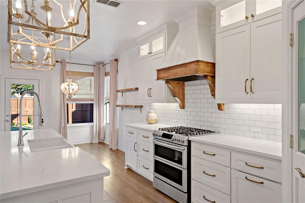 Kitchen featuring tasteful backsplash, an inviting chandelier, a sink, premium range hood, and double oven range