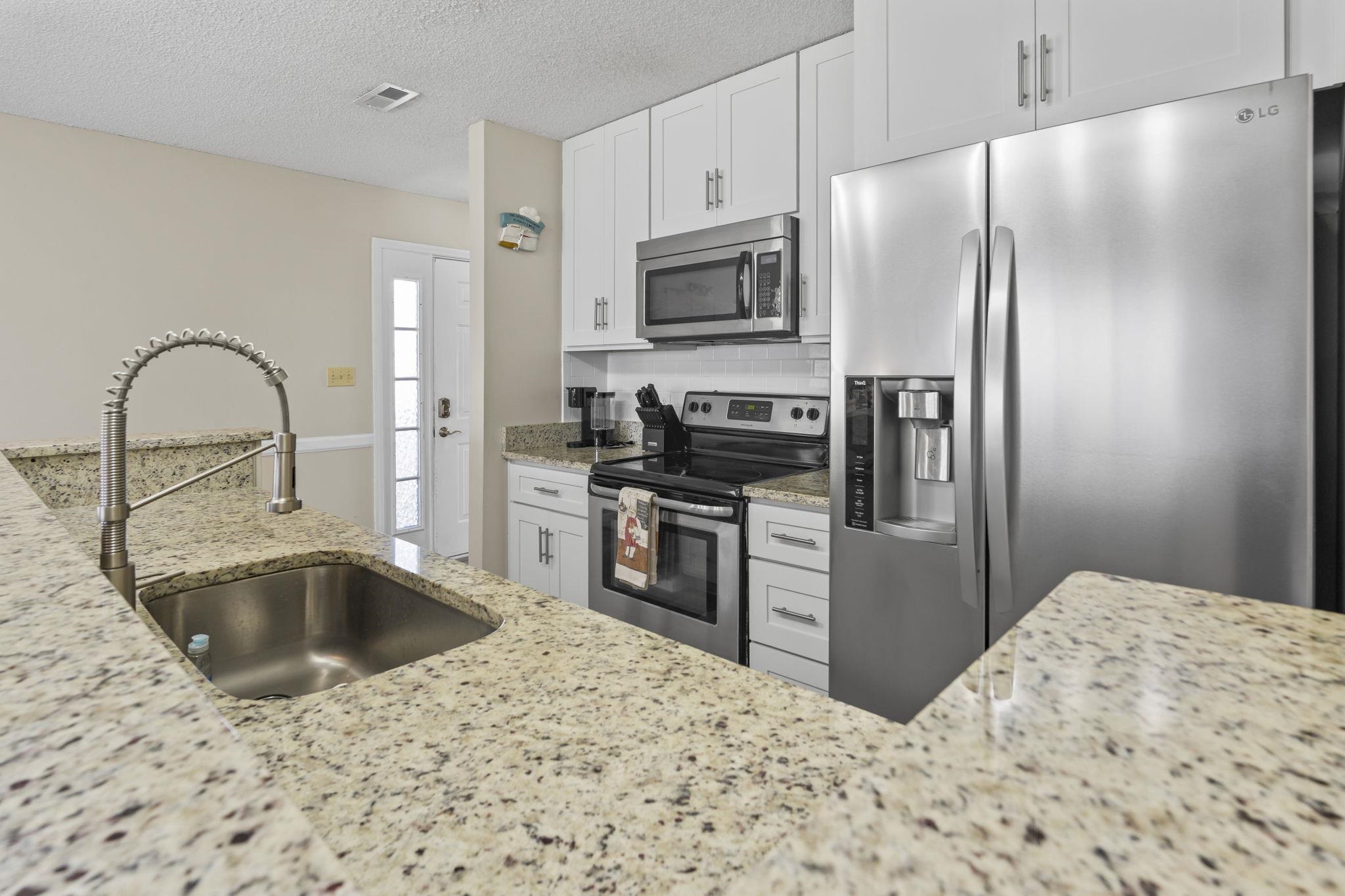 4353 Spa Drive, Unit 909 Little River, SC 29566 - Photo 13 of 39 Kitchen with stainless steel appliances, light stone counters, white cabinetry, a textured ceiling, and tasteful backsplash