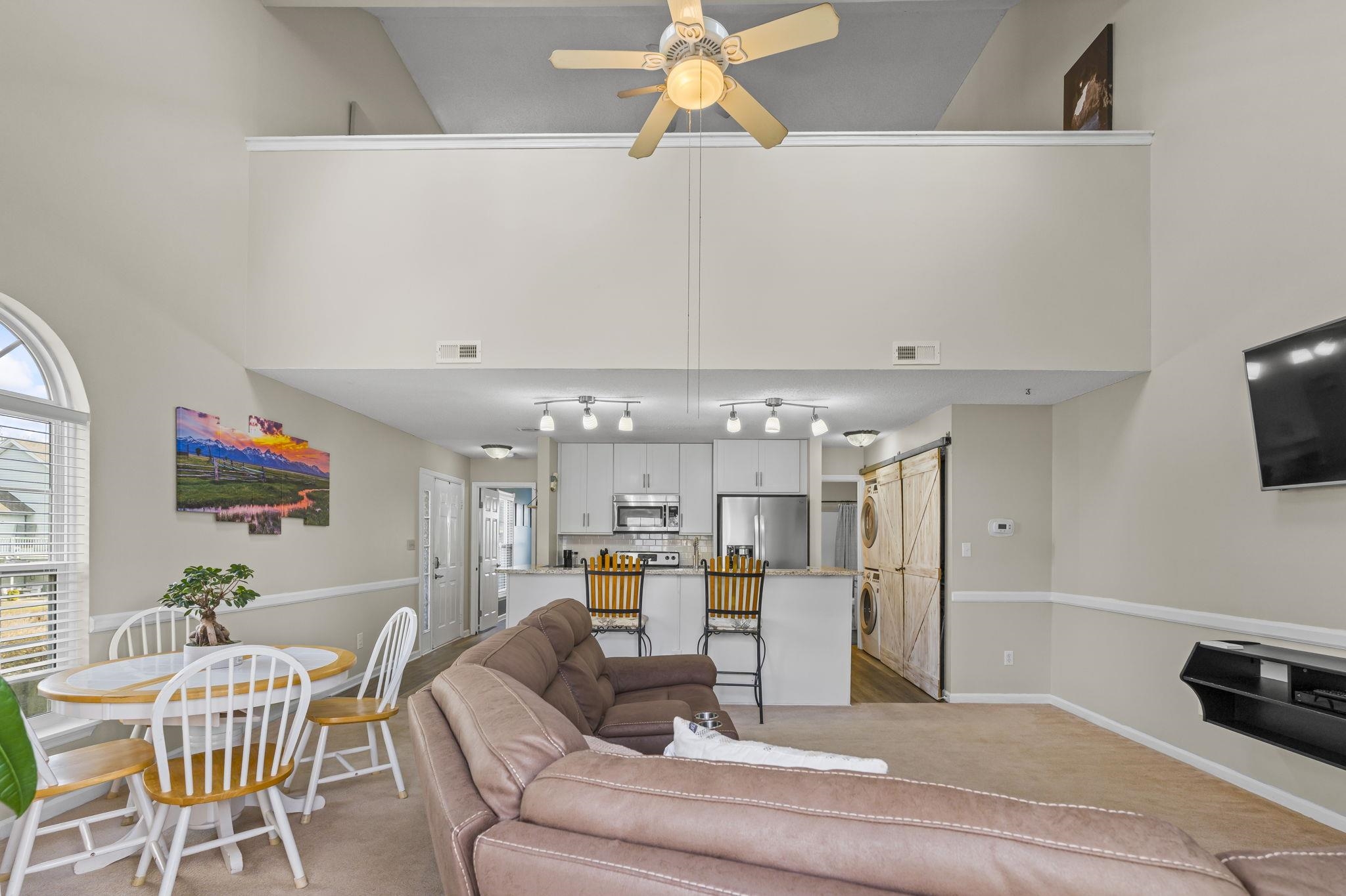 4353 Spa Drive, Unit 909 Little River, SC 29566 - Photo 6 of 39 Living area featuring a high ceiling, a barn door, light colored carpet, and ceiling fan