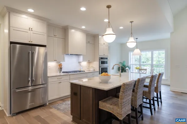 a kitchen with granite countertop a stove a sink island and chairs in it
