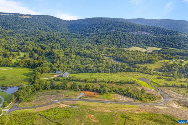 a front view of a house with a garden and lake view