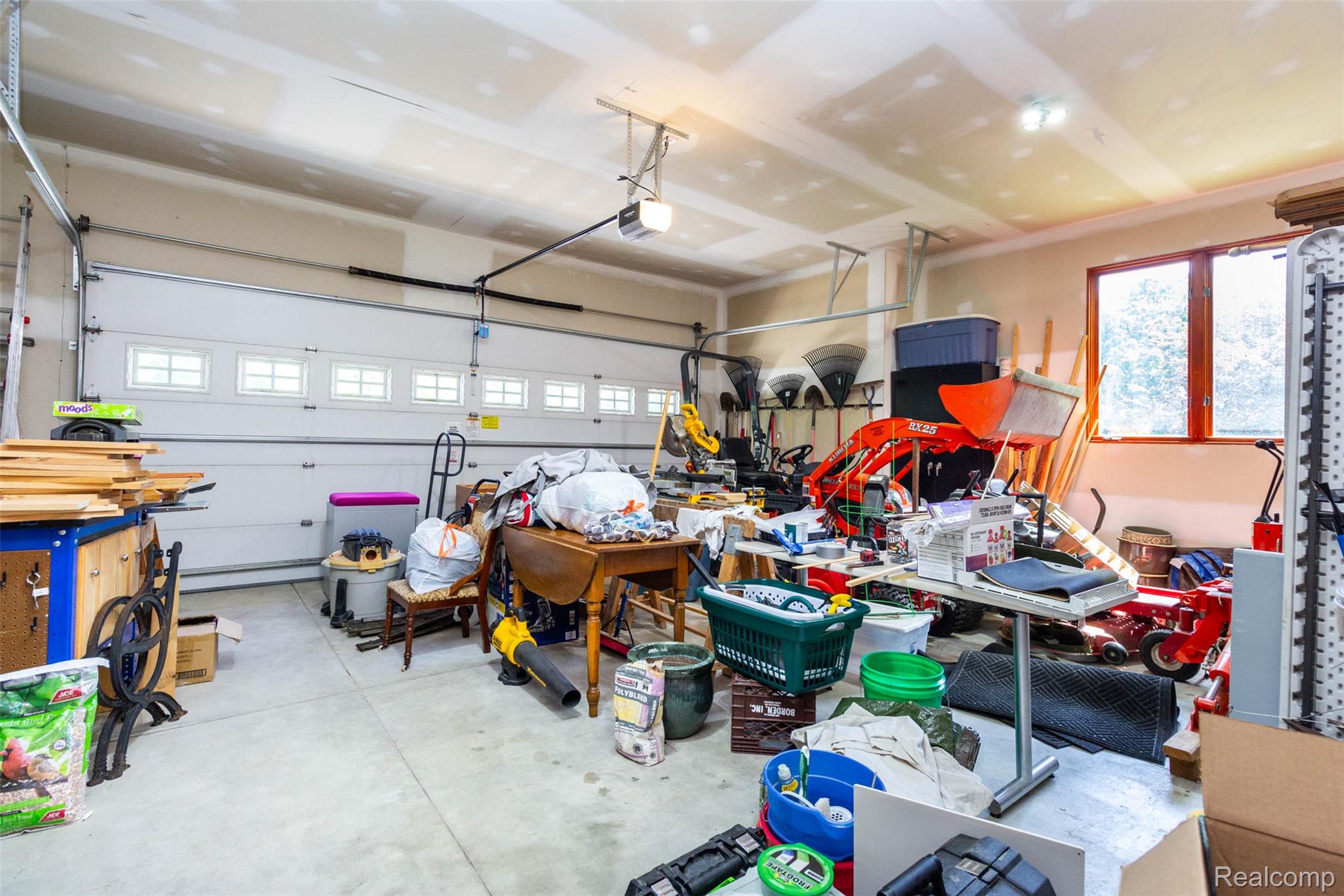 9887 Hadley Road Clarkston, MI 48348 - Photo 31 of 56 Spacious garage featuring a windowed overhead door, concrete flooring, upper wall window, painted walls, and overhead lighting