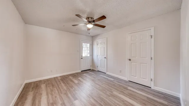 a view of an empty room with window and wooden floor