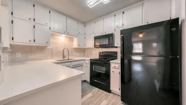 a kitchen with a refrigerator stove and white cabinets
