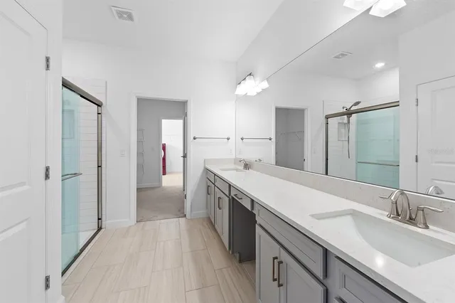 a spacious bathroom with a double vanity sink a mirror and a shower