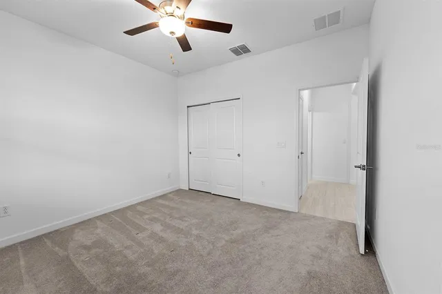 an empty room with ceiling fan and windows