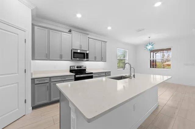 a kitchen with granite countertop a stove a sink and a microwave