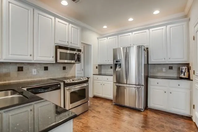 a kitchen with white cabinets and stainless steel appliances