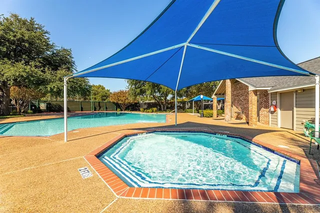 a view of swimming pool with lawn chairs under an umbrella