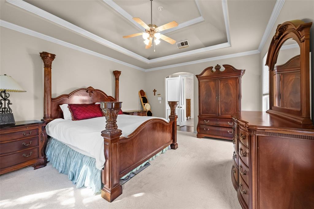 3904 Edna Valley Court Flower Mound, TX 75022 - Photo 19 of 36 a bedroom with a large bed and a chandelier