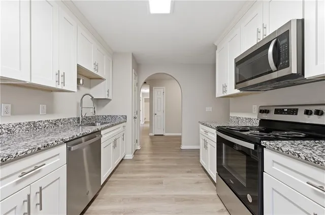 a kitchen with stainless steel appliances granite countertop a stove top oven a sink dishwasher and white cabinets with granite countertops