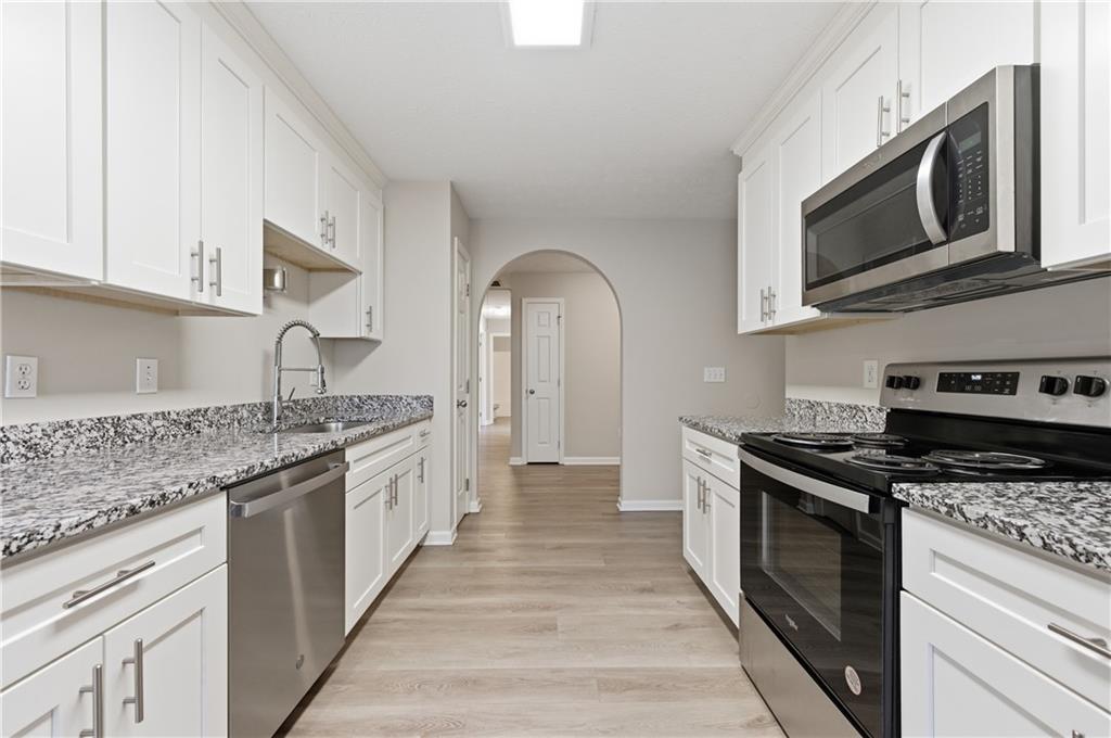 1730 Alcovy River Drive Dacula, GA 30019 - Photo 5 of 30 a kitchen with stainless steel appliances granite countertop a stove top oven a sink dishwasher and white cabinets with granite countertops