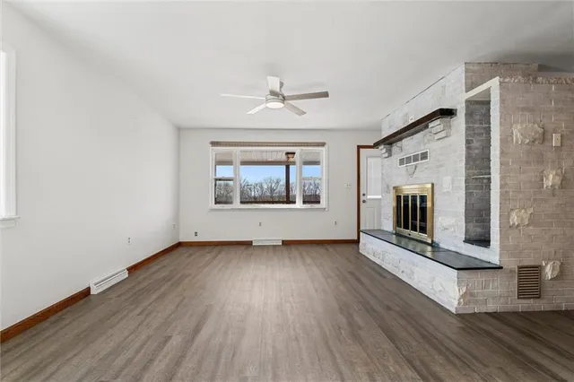 an empty room with wooden floor fireplace and windows