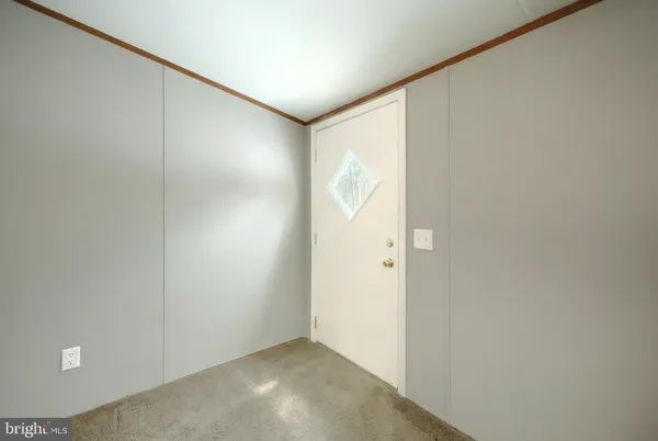 a view of an empty room with kitchen and a window