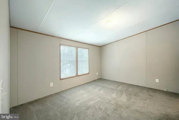 a view of an empty room with wooden floor and windows