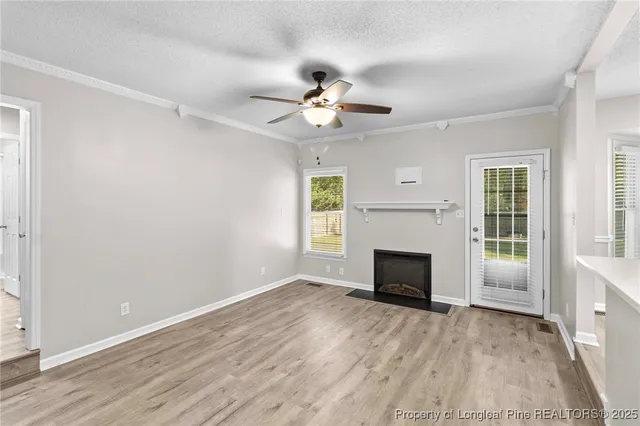 a view of an empty room with wooden floor fireplace and a window