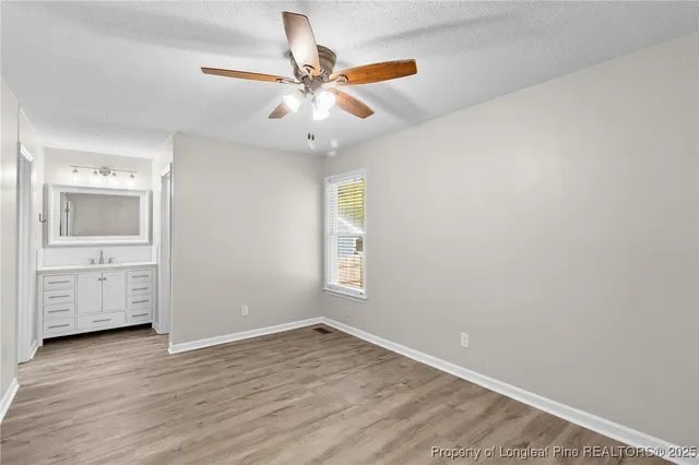 an empty room with wooden floor and a ceiling fan
