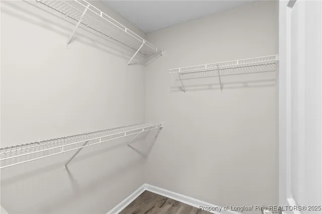 an empty room with wooden floor chandelier fan and windows