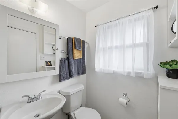 a bathroom with a sink vanity mirror and toilet