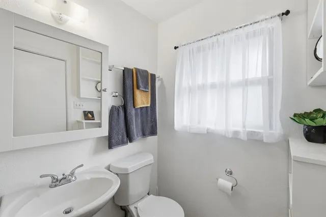 a bathroom with a sink vanity mirror and toilet