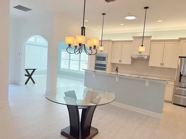 a kitchen with stainless steel appliances granite countertop a sink a counter space and a view of living room