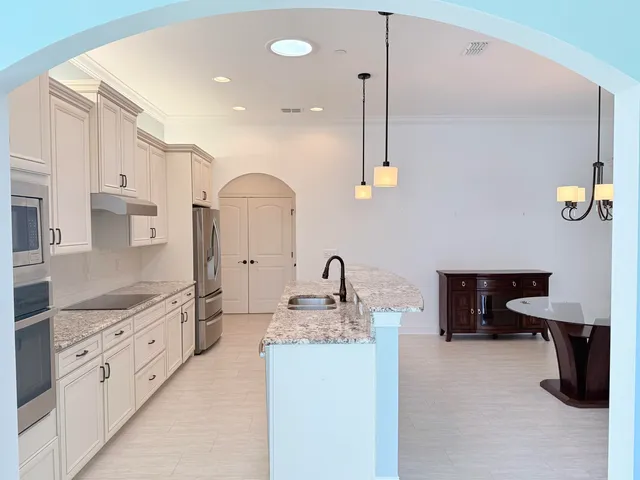 a kitchen with kitchen island granite countertop a sink a stove and refrigerator